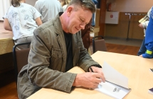 Uśmiechnięty mężczyzna podpisuje książkę 