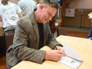 Uśmiechnięty mężczyzna podpisuje książkę 