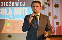 Elegancko ubrany mężczyzna na scenie mówi do mikrofonu 