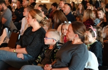 Kilkanaście osób siedzących i obserwujących koncert 