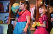 Dwie dziewczynki w jednakowych strojach śpiewają piosenkę na scenie 