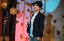 Chłopiec w kapeluszu śpiewający do mikrofonu ze sceny 