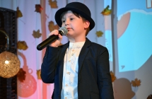 Chłopiec w kapeluszu śpiewa ze sceny do mikrofonu 