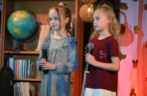 Dwie dziewczynki na scenie. Trzymają mikrofony. 