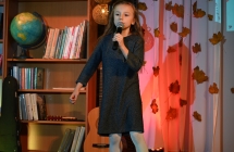 Dziewczynka na scenie, śpiewa do mikrofonu . 