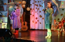 Dwie dziewczynki trzymające parasolki i śpiewające do mikrofonu 