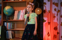 Uśmiechnięta dziewczynka śpiewająca ze sceny do mikrofonu 