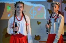 Dwie dziewczynki w ludowych strojach śpiewające na scenie 