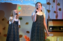 Dwie jednakowo ubrane dziewczynki wykonujące piosenkę na scenie 