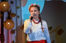 Dziewczynka w wianeczku i ubrana na ludowo wykonująca piosenkę 