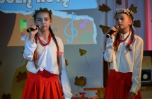 Dwie dziewczynki ubrane na ludowo podczas wykonywania piosenki na scenie 