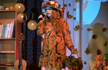 Młoda dziewczynka w charakterystycznym stroju śpiewa do mikrofonu. 