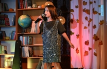 Dziewczynka w sukience w cekiny wykonująca utwór wokalny na scenie 