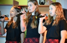 Trzy dziewczynki śpiewające na scenie do mikrofonów 