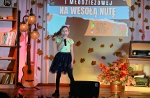 Młoda dziewczynka śpiewająca do mikrofonu ze sceny 