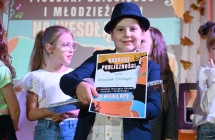 Uśmiechnięty chłopiec z dyplomem na scenie 