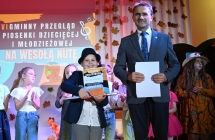 Mężczyzna oraz chłopiec. Chłopiec prezentuje się z dyplomem 