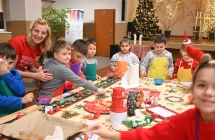 Uśmiechnięta kobieta i dzieci w trakcie mikołajkowego spotkania dla najmłodszych 