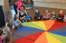 Dzieci wraz z opiekunkami bawiące się chustą edukacyjną 