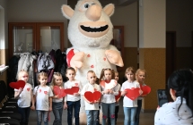 Dzieci z pluszowymi serduszkami przy animatorze w stroju olbrzymiej maskotki 