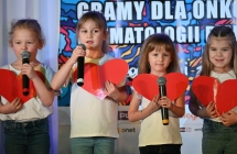 Cztery dziewczynki śpiewające do mikrofonu na scenie 