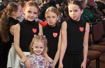 Trzy jednakowo ubrane dziewczynki, przed nimi mała dziewczynka 