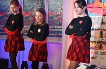 Trzy dziewczynki w jednakowych strojach podczas wykonywania układu tanecznego na scenie 