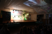 Grupa kilkudziesięciu uczniów oglądająca film o dinozaurze 
