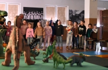 Zabawki - dinozaury, przed nimi grupa dzieci 