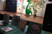 Wystawka książek z dinozaurami. W tle makieta dinozaura