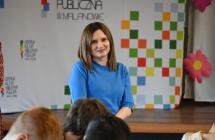 Uśmiechnięta kobieta, w tle baner z napisem - Centrum Kultury i Biblioteka Publiczna w Malanowie 