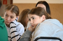 Trzy dziewczynki słuchające prowadzących warsztaty dziennikarskie 