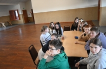 Grupa uczniów siedząca przy stole na warsztatach dziennikarskich 