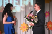 Mężczyzna wręczający kobiecie kwiaty na scenie. 