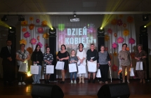 Kilkanaście kobiet na scenie - trzymają w rękach drobne upominki 