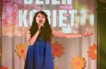 Kobieta w eleganckiej sukni śpiewająca do mikrofonu. 