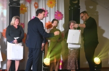 Dwoje mężczyzn wręczających upominki kobietom na scenie 