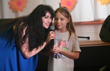 Kobieta i dziewczynka. Kobieta trzyma mikrofon do którego śpiewają we dwie 