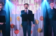 Troje mężczyzn na scenie - jeden śpiewa do mikrofonu 