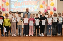 Mężczyzna z grupą dzieci na scenie. 