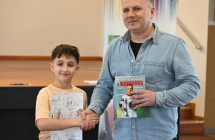 Uśmiechnięty mężczyzna wraz z chłopcem. Mężczyzna trzyma książkę - nagrodę 