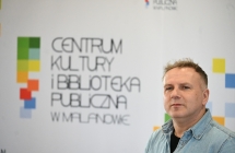 Mężczyzna na tle baneru z napisem - centrum kultury i biblioteka publiczna w malanowie 