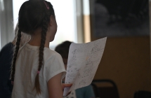 Dziewczynka w warkoczykach czytająca komiks z kartki 