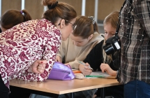 Kobieta mówiąca do dzieci siedzących przy stoliku 