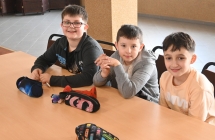 Troje uśmiechniętych chłopców siedzących przy stoliku 