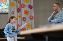 Mężczyzna stojący przy dziewczynce czytającej komiks 