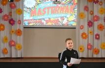 Chłopiec czytający komiks. Za nim baner z napisem - warsztaty komiksowe 