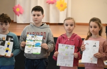 Dwoje chłopców i dwie dziewczynki trzymający przed sobą narysowane własnoręcznie komiksy 