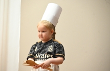 Dziewczynka na scenie. Na głowie ma kucharską czapkę 