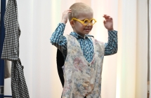 Radosny chłopiec w okularach i serdaczku odgrywający rolę aktorską 